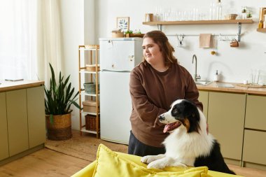 Down sendromlu genç bir kadın köpeğini okşuyor sıcak ve davetkar bir evde neşeli bir anı paylaşıyor..