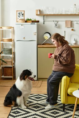 Down sendromlu bir kadın evinde rahatlıyor ve bir fincan kahve eşliğinde köpeğiyle anlarını paylaşıyor..