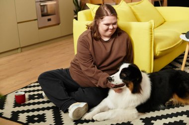 Genç bir kadın evinde mutluluğu yaşıyor, gülümsüyor ve yerde köpeğiyle vakit geçiriyor..