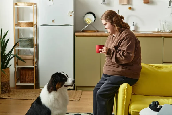 Evde dinlenen Down sendromlu genç bir kadın köpeğiyle sıcak bir anı paylaşıyor, çayını yudumluyor..