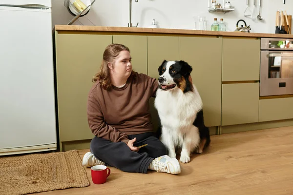 Down sendromlu genç bir kadın mutfakta köpeğiyle rahatlıyor..