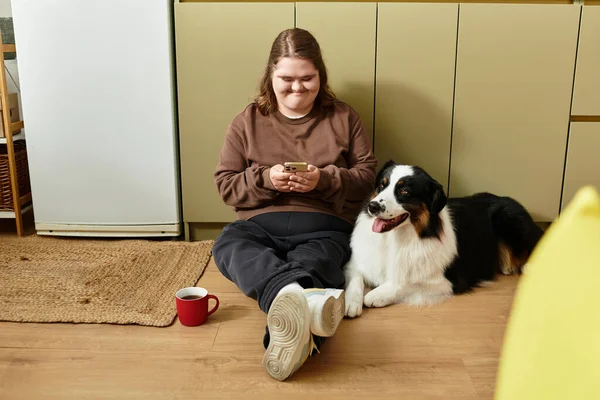 Down sendromlu genç bir kadın evinde rahatlıyor ve köpeğiyle vakit geçiriyor..