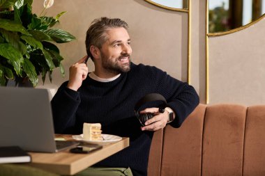 Yakındaki bir kafede tatlı yerken şık giyinmiş yakışıklı bir adam gülümsüyor..