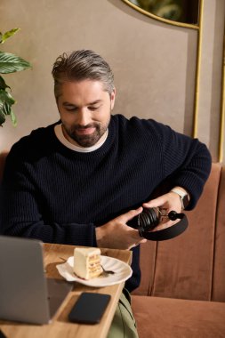 Olgun, yakışıklı bir adam, rahat bir kafede oturup, kulaklıklı kek ve müziğin tadını çıkarıyor..