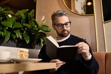 Moda kıyafetli yakışıklı bir adam, bir kafede durup günlüğünü yazıyor..