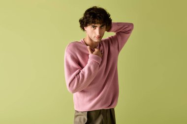 Şık bir adam kendine güveni tam pembe bir süveter ve gri pantolonla poz verir..