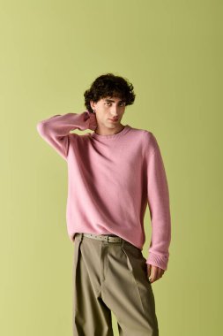 Yakışıklı adam kendine güveni olan şık bir elbiseyle parlak yeşil bir arka planda duruyor..