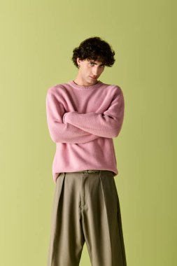 Yakışıklı adam zarif poz veriyor, şık bir iç mekan ve yeşil duvarlı modaya uygun kıyafetler giyiyor..