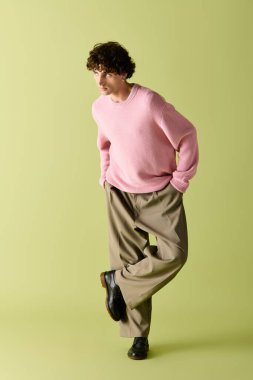 Şık giyinmiş yakışıklı bir adam, parlak bir arka plana karşı rahat bir poz verir..