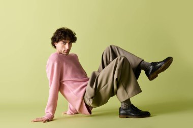 Yakışıklı adam, şık kıyafetler içinde zahmetsizce poz veriyor. Havalı bir ortamda günlük ve moda tarzları harmanlıyor..