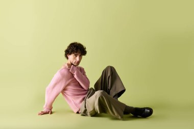 Zarif bir adam, yumuşak yeşil bir zemine güvenle oturur..