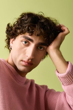 Pembe süveter giyen yakışıklı bir adam elini nazikçe uzatıyor ve gösteriş yapıyor..