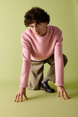 Yakışıklı bir adam yere çömelmiş, kendine has bir moda anlayışı sergiliyor..