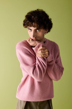 Şık bir adam kendine güvenerek poz veriyor, şık kıyafetini canlı bir arka plana vurguluyor..