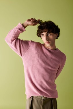 Modayı takip eden yakışıklı bir adam, komik bir şekilde saçını çekici bir ifadeyle şekillendiriyor..