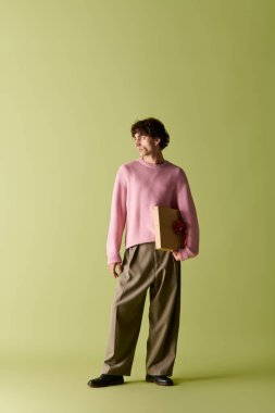 Moda kıyafetleri içinde yakışıklı bir adam elinde canlı bir klasörle güvenle duruyor..