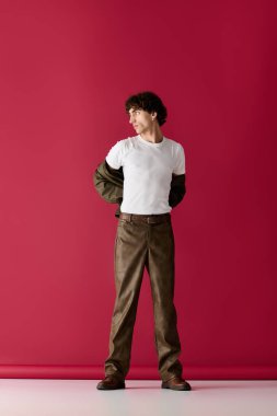 Yakışıklı adam şık kıyafetini cesur bir renk ortamında düzeltirken kendine güveni tam duruyor..