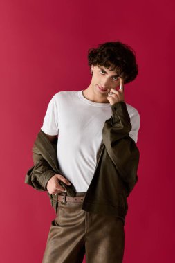 Şık bir adam renkli bir arkaplan karşısında kendine güvenen bir şekilde poz verir..