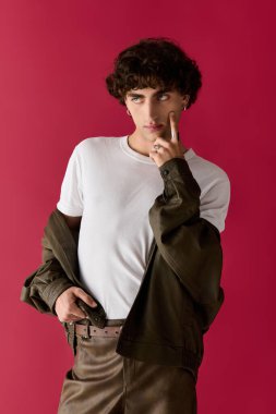 Yakışıklı bir adam, neşeli bir hareketle poz verirken şık giyiniyor, kendine güveni tam..