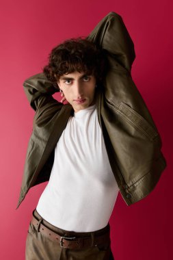 Kendine güvenen bir adam cesur ve renkli bir ortamda gösterişli modern giysilerle poz verir..