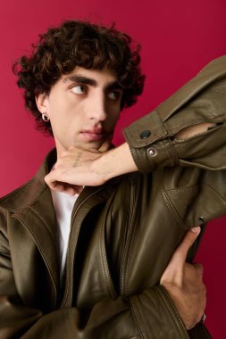 İyi giyimli bir adam özgüvenini ve çekiciliğini gösterirken cesur bir kırmızı arka plana karşı poz verir..