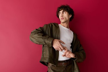 Şık giyinmiş yakışıklı bir adam canlı kırmızı bir duvara karşı şık bir bakış sergiliyor..