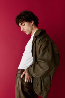 Şık bir adam kendine güvenerek ayakta duruyor, şık kıyafetini parlak bir arka plana vurguluyor..