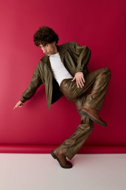 Şık bir adam cesur, kırmızı bir arka plana karşı özgüvenle poz veriyor, canlı bir moda sergiliyor..