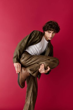 Şık bir adam özgüvenle poz verir, çarpıcı bir geçmişi olan cesur moda seçimleri sergiler..