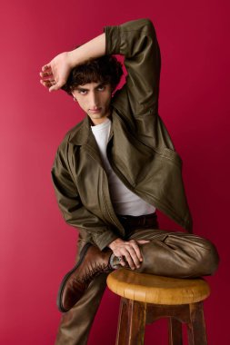 Şık bir birey, parlak bir arka plana karşı taburede zarifçe poz verir..