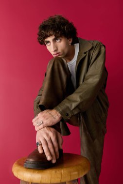 Moda giyinmiş yakışıklı bir adam kendine güvenen bir bakışla tabureye yaslanıyor..
