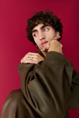 Şık bir adam canlı kırmızı bir arka plana karşı düşünceli bir şekilde poz verir, cazibesini sergiler..