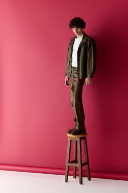 Kendinden emin bir adam, çarpıcı pembe bir odada çağdaş tarzda poz veriyor..