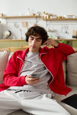 Şık giyinmiş yakışıklı adam telefonunu karıştırırken kulaklıkla müzik dinliyor..