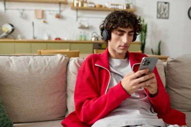 Moda kıyafetli yakışıklı adam rahatça otururken kulaklıkla müzik dinliyor..