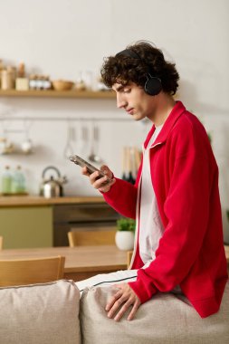 Şık giyinmiş yakışıklı adam otururken ve rahat bir şekilde telefonundan müzik dinliyor..