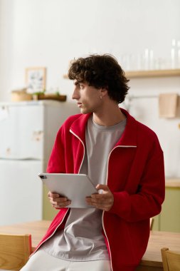 Şık giyinmiş yakışıklı bir adam sıcak bir mutfağa daldırılmış bir tablet tutuyor..