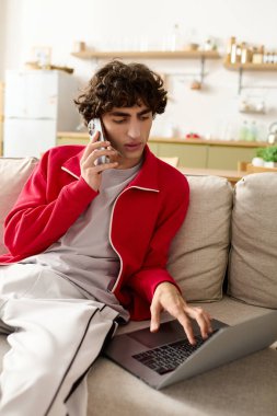 Yakışıklı bir adam dizüstü bilgisayarla uğraşırken bir telefon görüşmesi yapıyor, modern dekorda rahatlıyor..