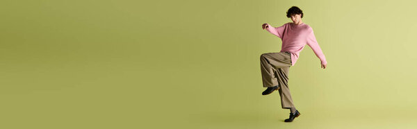 Man in trendy outfit showcases his fashion sense with a playful stance in a modern setting.