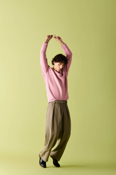 Красивый мужчина в розовом свитере и без штанов принимает динамичную позу, выражая уверенность.