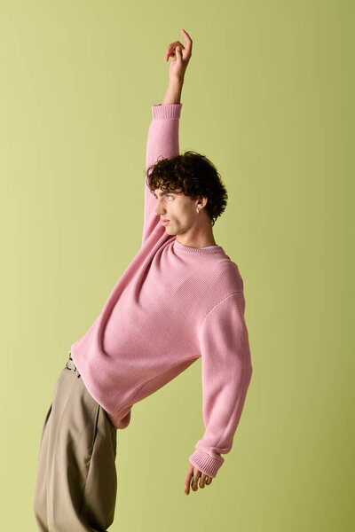 Стильный мужчина позирует игриво на ярком фоне, демонстрируя свой модный наряд.