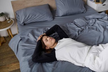 Genç bir kadın yatakta dinleniyor, yalnızlığın tadını çıkarıyor ve düşüncelerini yansıtıyor..