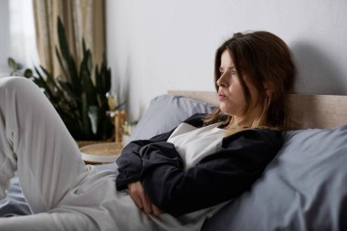 Genç bir kadın gününü yatağında geçirir, şık dairesinde sessizce yansıtır..