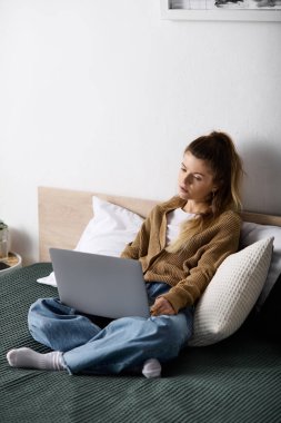 Genç bir kadın gününü yatakta dizüstü bilgisayarla geçirir. Arkadaşlığından keyif alır..