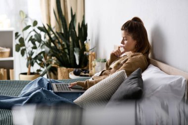 Genç bir kadın yatak odasında sakin bir gün geçirir. Yatakta uzanırken dizüstü bilgisayarıyla çalışır..