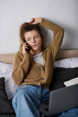 Genç bir kadın rahat dairesinde dinleniyor, yatakta gününün tadını çıkarırken telefonla konuşuyor..