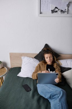 Genç bir kadın, modern bir apartman dairesinde cihazına odaklanarak gününün tadını çıkarıyor..