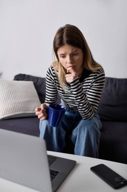 Modern dairesinde çalışan, kahvesini yudumlayan genç bir kadın.