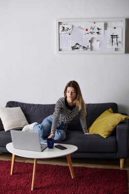 Genç bir kadın şık dairesinde dinleniyor, kanepede tembel bir günün tadını çıkarıyor..