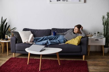 Genç bir kadın modern dairesinde rahatça uzanır, günlük strese ara verir..